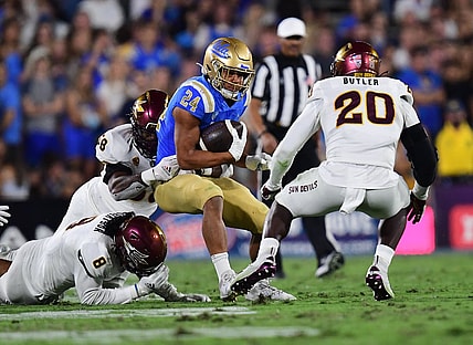 Oct 2, 2021; Pasadena, California, USA; UCLA Bruins running back Zach Charbonnet (24) runs the ball against Arizona State Sun Devils defensive lineman Joe Moore (58) linebacker Darien Butler (20) and linebacker Merlin Robertson (8) during the first half at Rose Bowl. Mandatory Credit: Gary A. Vasquez-USA TODAY Sports