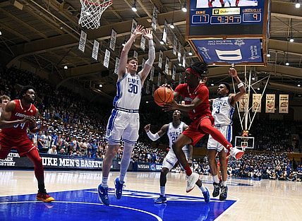 Feb 28, 2024; Durham, North Carolina, USA; Louisville Cardinals guard Ty-Laur Johnson (4) throws a pass around Duke Blue Devils center Kyle Filipowski (30) during the first half at Cameron Indoor Stadium. Mandatory Credit: Rob Kinnan-USA TODAY Sports