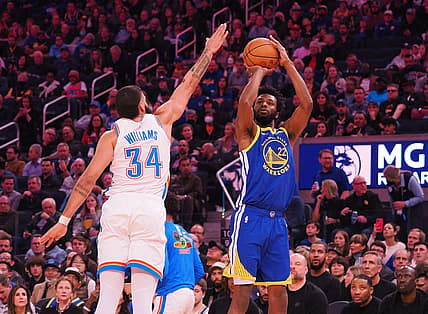 Feb 6, 2023; San Francisco, California, USA; Golden State Warriors small forward Andrew Wiggins (22) scores a three point basket against Oklahoma City Thunder shooting guard Kenrich Williams (34) during the second quarter at Chase Center. Mandatory Credit: Kelley L Cox-USA TODAY Sports