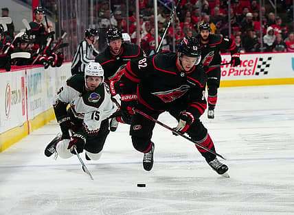 Jan 27, 2024; Raleigh, North Carolina, USA; Carolina Hurricanes center Jesperi Kotkaniemi (82) skates with the puck past Arizona Coyotes center Alexander Kerfoot (15) during the third period at PNC Arena. Mandatory Credit: James Guillory-USA TODAY Sports