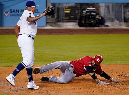 Apr 26, 2021; Los Angeles, California, USA; Cincinnati Reds right fielder Nick Castellanos (2) slide across home plate to score in the fourth inning as Los Angeles Dodgers starting pitcher Julio Urias (7) watches during the fourth inning at Dodger Stadium. Mandatory Credit: Robert Hanashiro-USA TODAY Sports