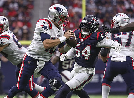 Oct 10, 2021; Houston, Texas, USA; New England Patriots quarterback Mac Jones (10) scrambles with the ball as Houston Texans defensive end Jake Martin (54) defends during the second quarter at NRG Stadium. Mandatory Credit: Troy Taormina-USA TODAY Sports