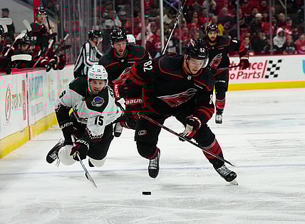 Jan 27, 2024; Raleigh, North Carolina, USA; Carolina Hurricanes center Jesperi Kotkaniemi (82) skates with the puck past Arizona Coyotes center Alexander Kerfoot (15) during the third period at PNC Arena. Mandatory Credit: James Guillory-USA TODAY Sports