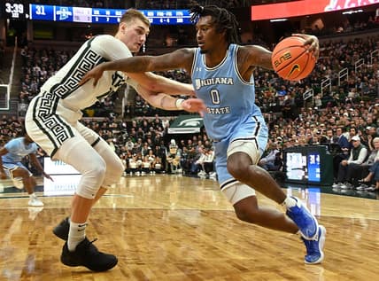 Dec 30, 2023; East Lansing, Michigan, USA; Indiana State Sycamores guard Xavier Bledson (0) drives against Michigan State Spartans center Carson Cooper (15) during the first half at Jack Breslin Student Events Center. Mandatory Credit: Dale Young-USA TODAY Sports