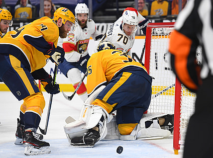 Mar 4, 2021; Nashville, Tennessee, USA; Nashville Predators defenseman Mattias Ekholm (14) watches as a shot by Florida Panthers right wing Patric Hornqvist (70) slides through the crease behind goaltender Pekka Rinne (35) during the second period at Bridgestone Arena. Mandatory Credit: Christopher Hanewinckel-USA TODAY Sports