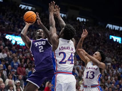 Jan 6, 2024; Lawrence, Kansas, USA; TCU Horned Frogs forward Emanuel Miller (2) shoots against Kansas Jayhawks forward K.J. Adams Jr. (24) and guard Elmarko Jackson (13) during the first half at Allen Fieldhouse. Mandatory Credit: Jay Biggerstaff-USA TODAY Sports