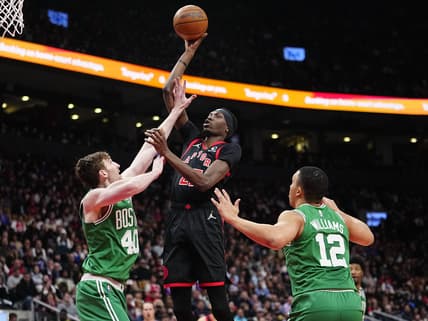 Mar 28, 2022; Toronto, Ontario, CAN; Toronto Raptors forward Chris Boucher (25) goes up to make a basket as Boston Celtics forward Luke Kornet (40) and Boston Celtics forward Grant Williams (12) defend during the first half at Scotiabank Arena. Mandatory Credit: John E. Sokolowski-USA TODAY Sports