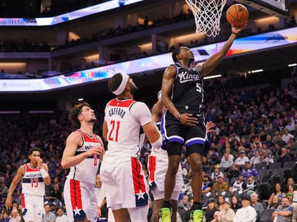 Dec 18, 2023; Sacramento, California, USA; Sacramento Kings guard De'Aaron Fox (5) scores a layup against Washington Wizards center Daniel Gafford (21) during the second quarter at Golden 1 Center. Mandatory Credit: Kelley L Cox-USA TODAY Sports