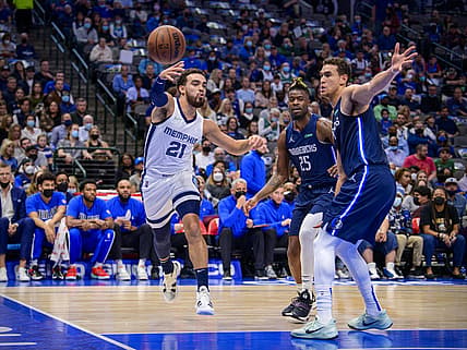 Dec 4, 2021; Dallas, Texas, USA; Memphis Grizzlies guard Tyus Jones (21) passes the ball past Dallas Mavericks forward Reggie Bullock (25) and center Dwight Powell (7) during the first quarter at the American Airlines Center. Mandatory Credit: Jerome Miron-USA TODAY Sports