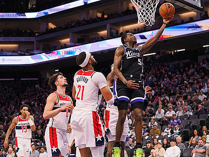 Dec 18, 2023; Sacramento, California, USA; Sacramento Kings guard De'Aaron Fox (5) scores a layup against Washington Wizards center Daniel Gafford (21) during the second quarter at Golden 1 Center. Mandatory Credit: Kelley L Cox-USA TODAY Sports