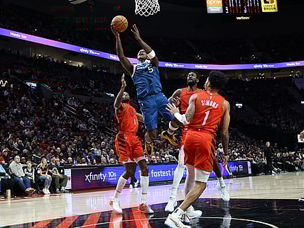 Feb 13, 2024; Portland, Oregon, USA;  Minnesota Timberwolves guard Anthony Edwards (5) shoots the ball over Portland Trail Blazers forward Jerami Grant (9), center Deandre Ayton (2), and guard Anfernee Simons (1) in the second quarter at Moda Center. Mandatory Credit: Jaime Valdez-USA TODAY Sports