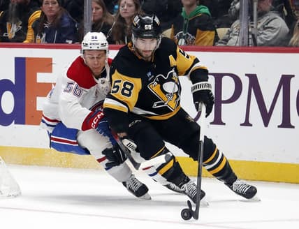 Jan 27, 2024; Pittsburgh, Pennsylvania, USA;  Pittsburgh Penguins defenseman Kris Letang (58) moves the puck ahead of Montreal Canadiens right wing Jesse Ylonen (56) during the second period  at PPG Paints Arena. Mandatory Credit: Charles LeClaire-USA TODAY Sports