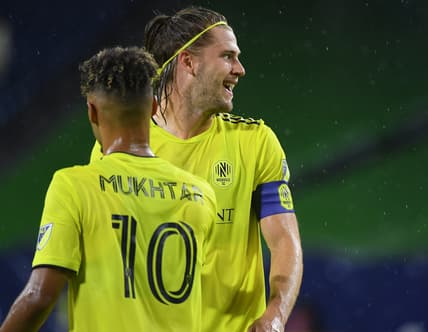 Aug 18, 2021; Nashville, TN, USA; Nashville SC defender Walker Zimmerman (25) and Nashville SC midfielder Hany Mukhtar (10) celebrate after a goal by Nashville SC forward C.J. Sapong (not pictured) during the first half against the Orlando City at Nissan Stadium. Mandatory Credit: Christopher Hanewinckel-USA TODAY Sports