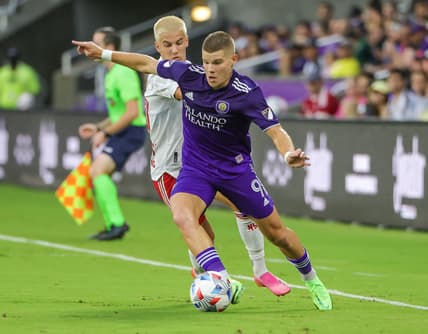 Jul 3, 2021; Orlando, Florida, USA; Orlando City forward Chris Mueller (9) kicks the ball in front of New York Red Bulls defender John Tolkin (47) during the first half at Orlando City Stadium. Mandatory Credit: Mike Watters-USA TODAY Sports