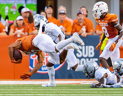 Sep 18, 2021; Austin, Texas; Texas Longhorns running back Bijan Robinson (5) goes airborne after being tripped up by Rice Owl defenders during the first quarter at Darrell K Royal-Texas Memorial Stadium. Mandatory Credit: John Gutierrez-USA TODAY Sports