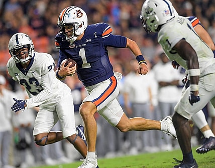 Auburn Tigers quarterback Payton Thorne (1) splts the Samford defenders, defensive back Devin Smith (23) and defensive back Kourtlan Marsh (1) as he carries for a touchdown during second half action in the AU vs. Samford game at Jordan-Hare Stadium in the AU campus in Auburn, Ala., on Saturday September 16, 2023.