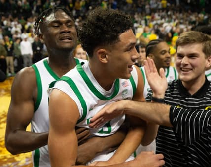 Oregon   s Jackson Shelstad, center, is mobbed by teammates after sinking the game winning shot against Michigan in overtime at Matthew Knight Arena in Eugene Saturday, Dec 2, 2023.
