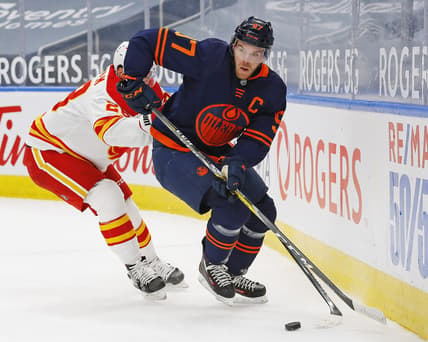 Feb 20, 2021; Edmonton, Alberta, CAN; Edmonton Oilers forward Connor McDavid (97) moves the puck past Calgary Flames forward Elias Lindholm (28) during the first period at Rogers Place. Mandatory Credit: Perry Nelson-USA TODAY Sports