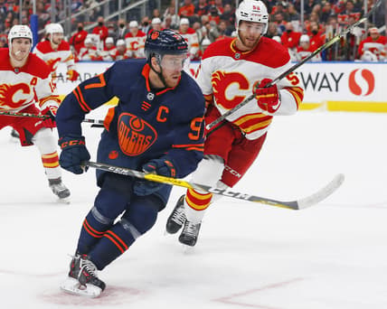 Oct 16, 2021; Edmonton, Alberta, CAN; Edmonton Oilers forward Connor McDavid (97) and Calgary Flames defensemen Noah Hanifin (55) chase a loose puck during the third period at Rogers Place. Mandatory Credit: Perry Nelson-USA TODAY Sports