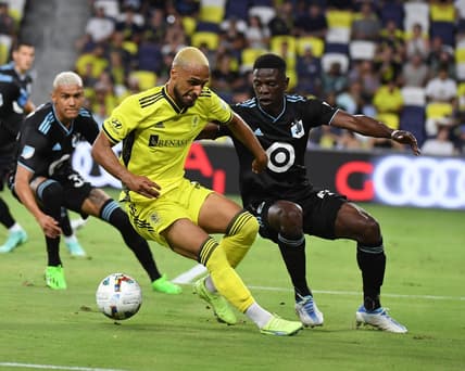 Aug 14, 2022; Nashville, Tennessee, USA; Nashville SC midfielder Hany Mukhtar (10) handles the ball against Minnesota United FC defender Bakaye Dibassy (12) during the second half at Geodis Park. Mandatory Credit: Christopher Hanewinckel-USA TODAY Sports