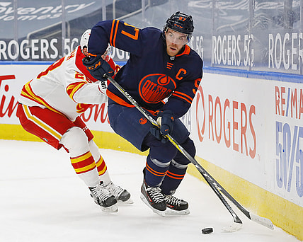 Feb 20, 2021; Edmonton, Alberta, CAN; Edmonton Oilers forward Connor McDavid (97) moves the puck past Calgary Flames forward Elias Lindholm (28) during the first period at Rogers Place. Mandatory Credit: Perry Nelson-USA TODAY Sports