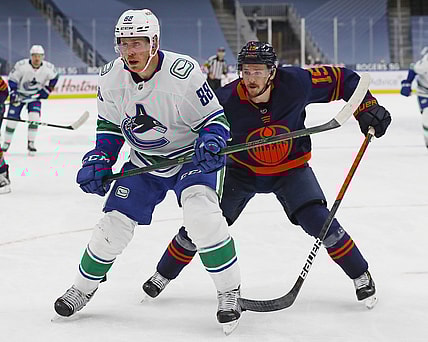 May 8, 2021; Edmonton, Alberta, CAN; Vancouver Canucks defensemen Nate Schmidt (88) and Edmonton Oilers forward Josh Archibald (15) chase a loose puck during the third period at Rogers Place. Mandatory Credit: Perry Nelson-USA TODAY Sports