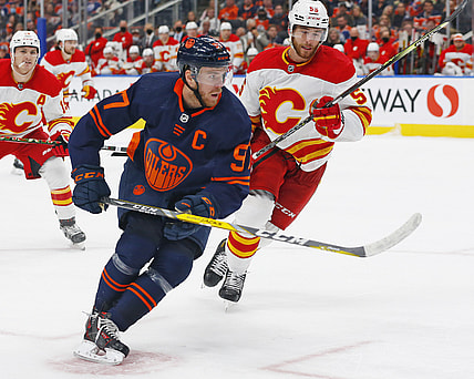 Oct 16, 2021; Edmonton, Alberta, CAN; Edmonton Oilers forward Connor McDavid (97) and Calgary Flames defensemen Noah Hanifin (55) chase a loose puck during the third period at Rogers Place. Mandatory Credit: Perry Nelson-USA TODAY Sports