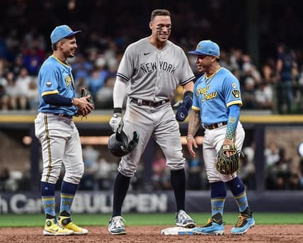 Sep 16, 2022; Milwaukee, Wisconsin, USA; New York Yankees center fielder Aaron Judge (99) talks to Milwaukee Brewers shortstop Willy Adames (27) and second baseman Kolten Wong (16) during a pause in the game in the second inning at American Family Field. Mandatory Credit: Benny Sieu-USA TODAY Sports