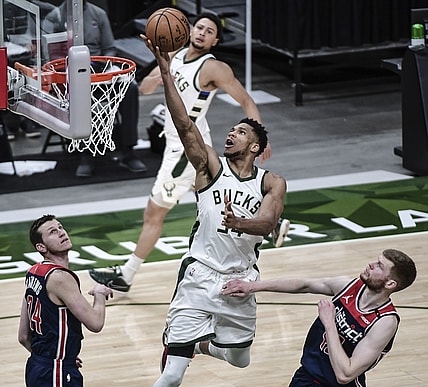 May 5, 2021; Milwaukee, Wisconsin, USA; Milwaukee Bucks forward Giannis Antetokounmpo (34) scores a basket against Washington Wizards guard Garrison Mathews (24) and forward Davis Bertans (42) in the fourth quarter at Fiserv Forum. Mandatory Credit: Benny Sieu-USA TODAY Sports