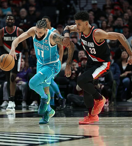 Feb 25, 2024; Portland, Oregon, USA; Charlotte Hornets forward Cody Martin (11) advances the ball past Portland Trail Blazers forward Toumani Camara (33) in the second quarter at Moda Center. Mandatory Credit: Jaime Valdez-USA TODAY Sports