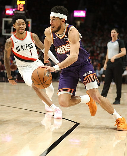 Dec 19, 2023; Portland, Oregon, USA; Phoenix Suns guard Devin Booker (1) drives the ball past Portland Trail Blazers guard Anfernee Simons (1) in the third quarter at Moda Center. Mandatory Credit: Jaime Valdez-USA TODAY Sports