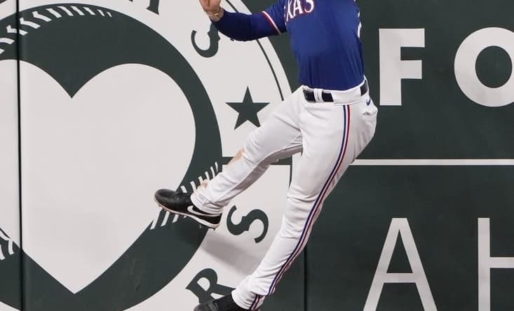 Mar 28, 2023; Arlington, Texas, USA; Texas Rangers left fielder Clint Frazier (77) leaps but is unable to catch the triple hit by Kansas City Royals senior director of hitting performance, major league hitting coach Alec Zumwalt (31) during the eighth inning of an exhibition game at Globe Life Field. Mandatory Credit: Jim Cowsert-USA TODAY Sports