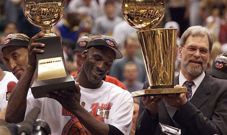 Michael Jordan holds the MVP trophy and coach Phil Jackson holds the championship trophy after the Bulls beat the Jazz to win their sixth title in 1998