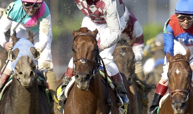 Jockey Jose Santos raised his hand in victory after he rode Funny Cide to a 1-length triumph over Empire Maker, left, in the 129th Kentucky Derby yesterday at Churchill Downs. May 3, 2003