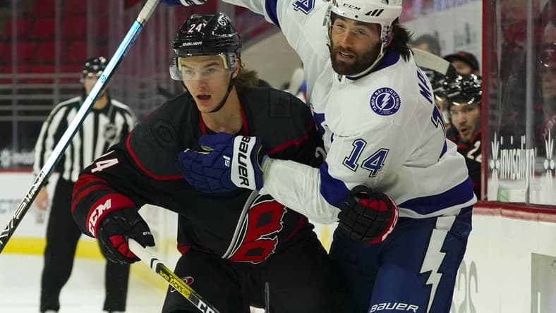 Jan 28, 2021; Raleigh, North Carolina, USA; Carolina Hurricanes defensemen Jake Bean (24) and Tampa Bay Lightning left wing Pat Maroon (14 watch the play during the first period at PNC Arena. Mandatory Credit: James Guillory-USA TODAY Sports