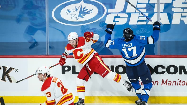 Feb 1, 2021; Winnipeg, Manitoba, CAN; Calgary Flames defenseman Nikita Nesterov (89) and Winnipeg Jets forward Adam Lowry (17) react to a collision during the first period at Bell MTS Place. Mandatory Credit: Terrence Lee-USA TODAY Sports