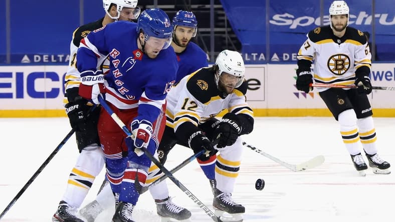 Feb 10, 2021; New York, New York, USA; Alexis Lafreniere #13 of the New York Rangers and Craig Smith #12 of the Boston Bruins battle for the puck during the first period at Madison Square Garden. Mandatory Credit: Bruce Bennett/Pool Photo-USA TODAY Sports