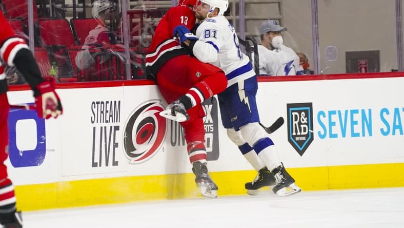Feb 20, 2021; Raleigh, North Carolina, USA; Carolina Hurricanes left wing Warren Foegele (13) is checked by Tampa Bay Lightning defenseman Erik Cernak (81) at PNC Arena. Mandatory Credit: James Guillory-USA TODAY Sports