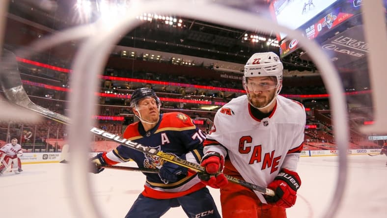 Feb 27, 2021; Sunrise, Florida, USA; Carolina Hurricanes defenseman Brett Pesce (22) gets push against the glass by Florida Panthers right wing Patric Hornqvist (70) during the second period at BB&T Center. Mandatory Credit: Sam Navarro-USA TODAY Sports