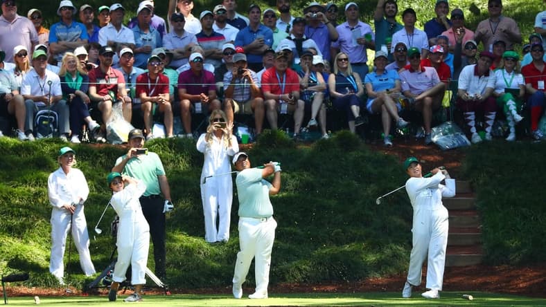 Apr 10, 2019; Augusta, GA, USA; Kiradech Aphibarnrat of Thailand (center) hits his tee shot with two guests during the Par 3 Contest at Augusta National Golf Club. Mandatory Credit: Rob Schumacher-USA TODAY Sports