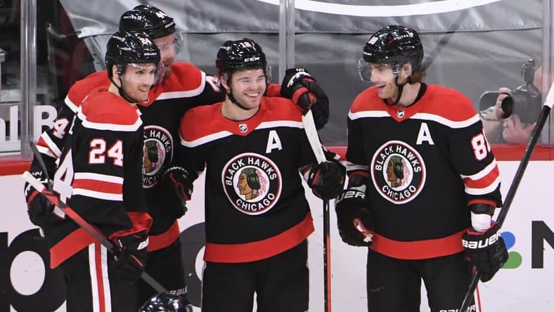 Feb 28, 2021; Chicago, Illinois, USA; Chicago Blackhawks left wing Alex DeBrincat (center) celebrates his goal against the Detroit Red Wings during the third period at United Center. Mandatory Credit: David Banks-USA TODAY Sports