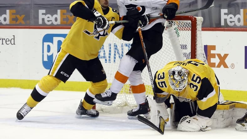 Mar 4, 2021; Pittsburgh, Pennsylvania, USA; Pittsburgh Penguins center Sidney Crosby (87) defends Philadelphia Flyers left wing Scott Laughton (21) as Pittsburgh Penguins goaltender Tristan Jarry (35) covers the puck after a save during the second period at PPG Paints Arena. Mandatory Credit: Charles LeClaire-USA TODAY Sports