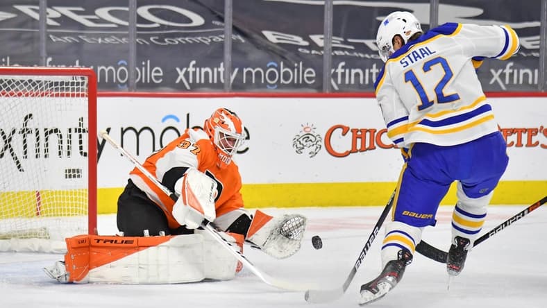 Mar 9, 2021; Philadelphia, Pennsylvania, USA; Philadelphia Flyers goaltender Brian Elliott (37) makes a save as Buffalo Sabres center Eric Staal (12) tries to control the rebound during the second period at Wells Fargo Center. Mandatory Credit: Eric Hartline-USA TODAY Sports