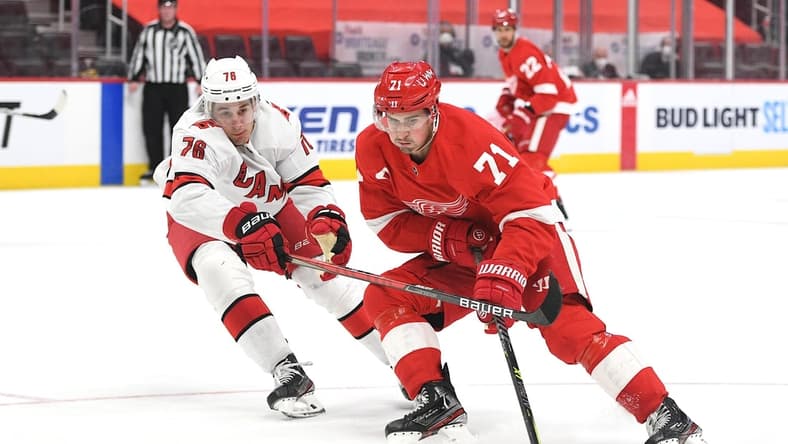 Mar 16, 2021; Detroit, Michigan, USA; Detroit Red Wings center Dylan Larkin (71) skates the puck up ice against Carolina Hurricanes defenseman Brady Skjei (76) during the second period at Little Caesars Arena. Mandatory Credit: Tim Fuller-USA TODAY Sports