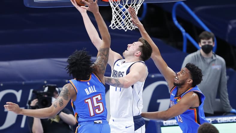 Mar 29, 2021; Oklahoma City, Oklahoma, USA; Dallas Mavericks guard Luka Doncic (77) goes to the basket between Oklahoma City Thunder forward Josh Hall (15) and forward Tony Bradley (13) during the first quarter at Chesapeake Energy Arena. Mandatory Credit: Alonzo Adams-USA TODAY Sports