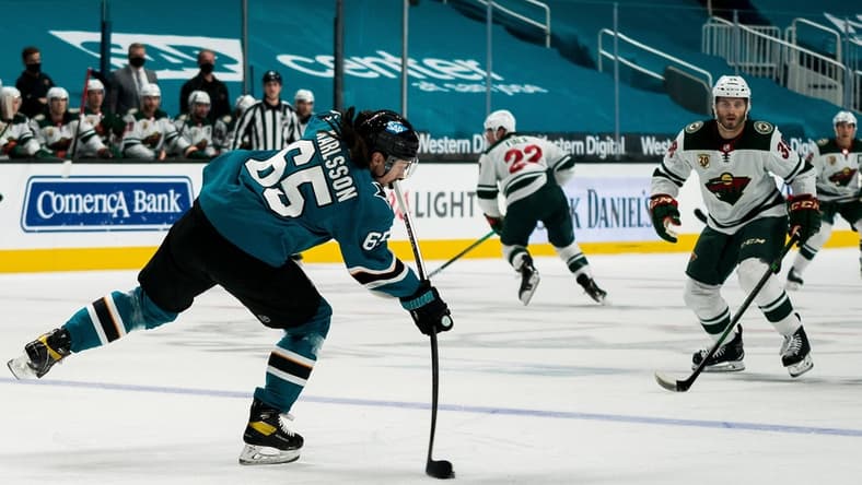 Mar 29, 2021; San Jose, California, USA; San Jose Sharks defenseman Erik Karlsson (65) passes the puck against Minnesota Wild right wing Ryan Hartman (38) during the first period at SAP Center at San Jose. Mandatory Credit: Neville E. Guard-USA TODAY Sports
