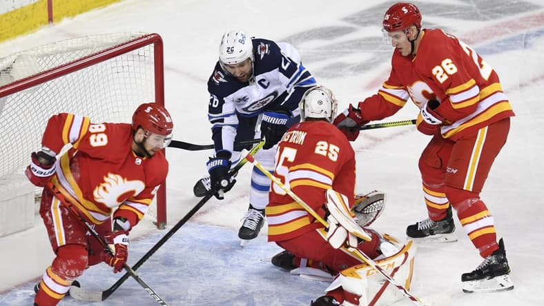Mar 29, 2021; Calgary, Alberta, CAN; Winnipeg Jets forward Blake Wheeler (26) battles for the puck with Calgary Flames defenseman Nikita Nesterov (89) goalie Jacob Markstrom (25) and defenseman Michael Stone (26) during the second period at Scotiabank Saddledome. Mandatory Credit: Candice Ward-USA TODAY Sports