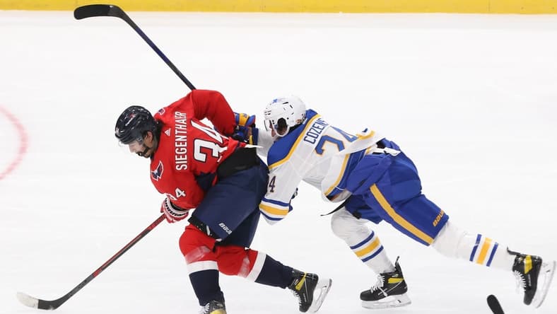 Jan 22, 2021; Washington, District of Columbia, USA; Washington Capitals defenseman Jonas Siegenthaler (34) battles for the puck with Buffalo Sabres center Dylan Cozens (24) in the second period at Capital One Arena. Mandatory Credit: Geoff Burke-USA TODAY Sports