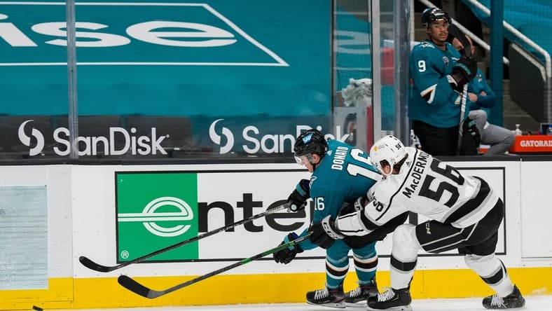 Mar 24, 2021; San Jose, California, USA; San Jose Sharks center Ryan Donato (16) and Los Angeles Kings defenseman Kurtis MacDermid (56) reaches for the puck during the second period at SAP Center at San Jose. Mandatory Credit: Stan Szeto-USA TODAY Sports
