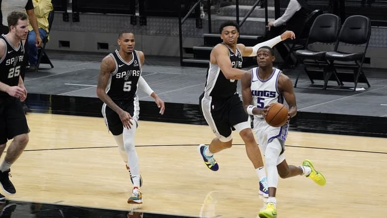 Mar 31, 2021; San Antonio, Texas, USA; Sacramento Kings guard De'Aaron Fox (5) drives to the basket past San Antonio Spurs forward Keldon Johnson (3) and guard Dejounte Murray (5) and center Jakob Poeltl (25) look on in the third quarter at AT&T Center. Mandatory Credit: Scott Wachter-USA TODAY Sports